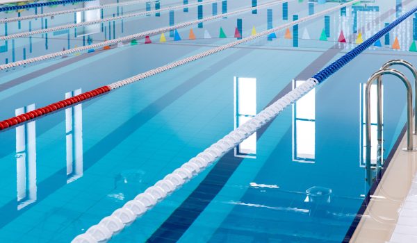 Swimming pool with marked red and white lanes. Empty swimming pool without people with quiet standing water. Water sports in indoor pool.